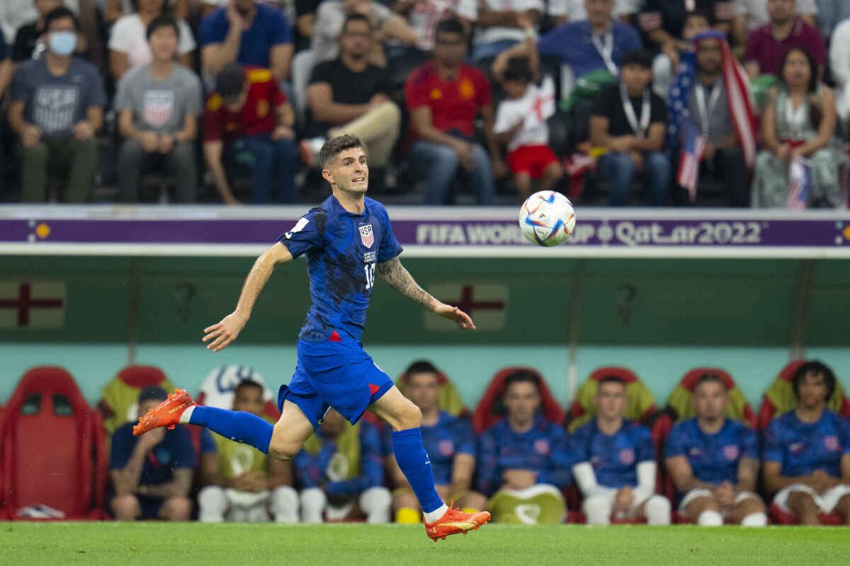 Christian Pulisic runs toward the ball in front of the U.S. soccer team's bench at the World Cup