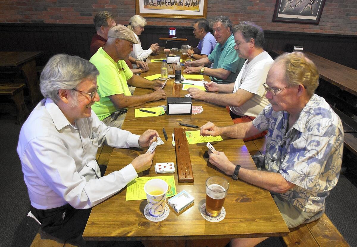Players -- including Barry Mednick, bottom left, and JJ Stansfield -- sit across from each other and mix it up during weekly cribbage game at a Lampost Pizza location in Huntington Beach.