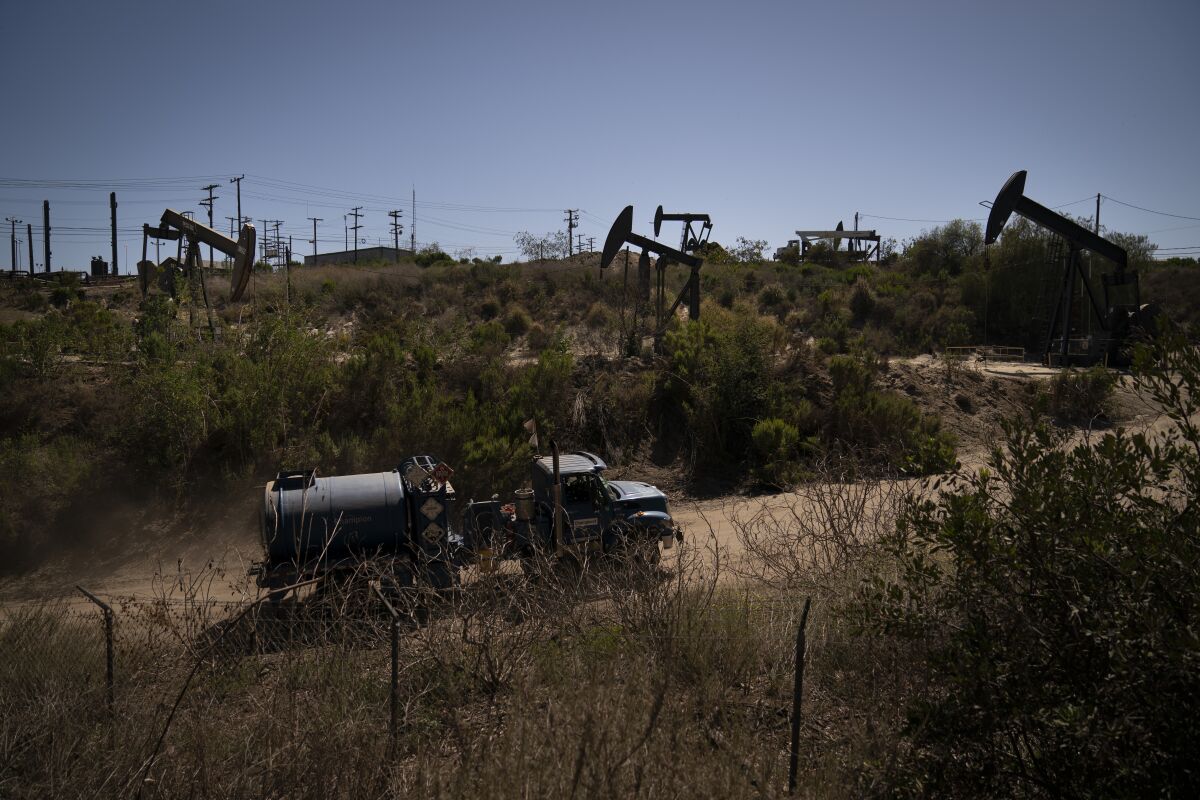 A truck drives past pump jacks operating at the Inglewood Oil Field, Thursday, June 10, 2021, in Los Angeles. (AP Photo/Jae C. Hong)