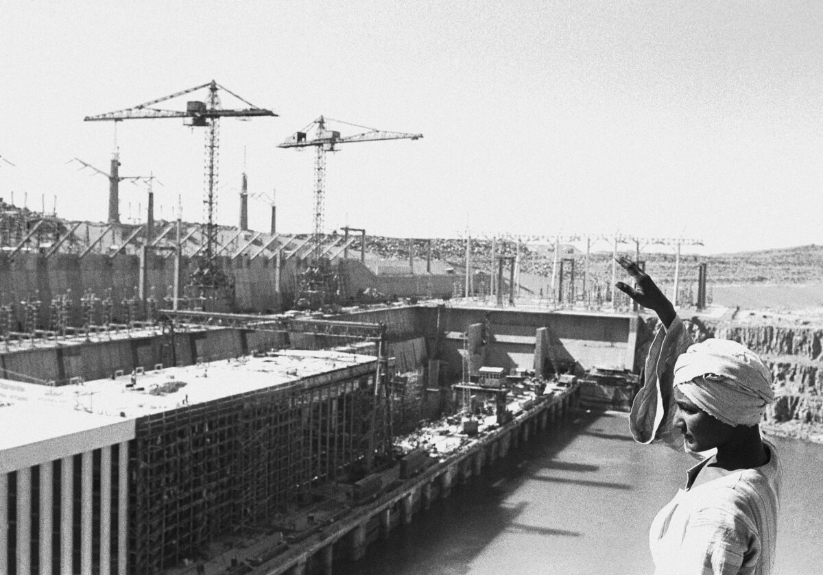 FILE - In this Feb. 27, 1968 file photo, an Egyptian worker waves as he stands on top of a rock overlooking the partly constructed power station on the Aswan High Dam, Egypt. Egyptians are marking 50 years since the inauguration of the Nile dam, a massive feat of construction that has shaped the course of modern-day Egypt. It spared it from seasonal droughts and flooding, and generated electricity. (AP Photo, File)
