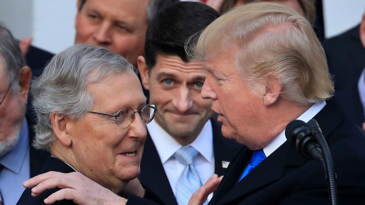 President Donald Trump congratulates Senate Majority Leader Mitch McConnell of Ky., while House Speaker Paul Ryan of Wis. watches, on the tax legislation at the White House in Washington on Dec. 20.