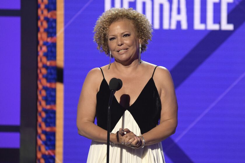A woman with short curly hair accepts an award onstage