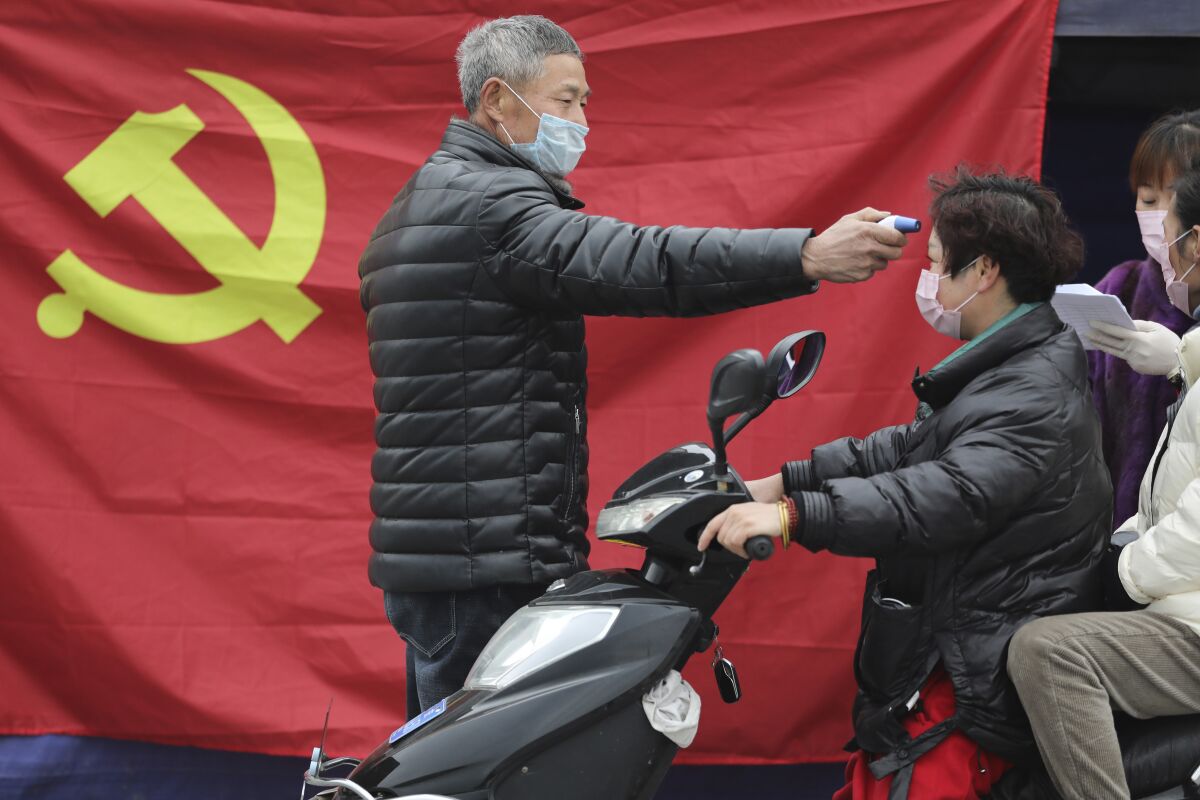 A volunteer takes the temperature of a scooter driver in Hangzhou, China.