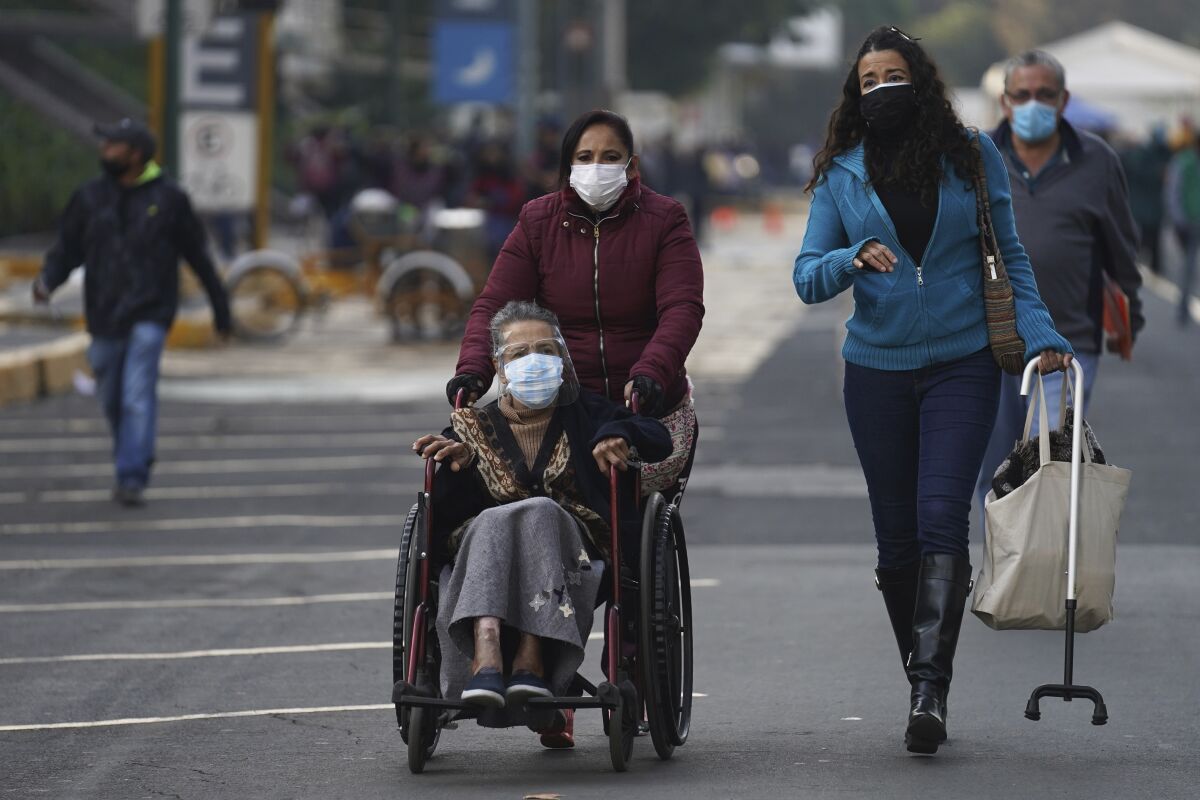 Three women, one in a wheelchair, head to a vaccine clinic in Mexico City