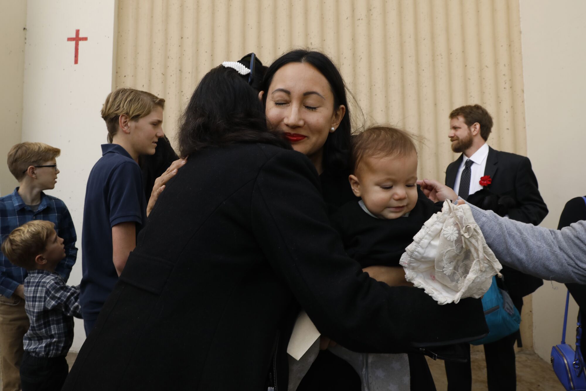 Kristenne Reidy gets a hug while holding her daughter, Joan Reidy, 3, after the funeral service.