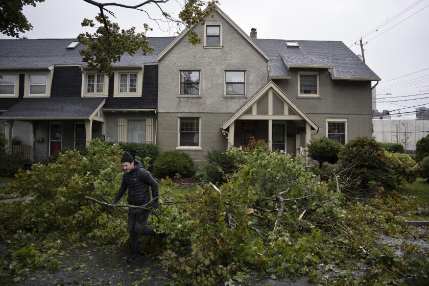 A man clears limbs and debris from his street as post tropical storm Fiona causes widespread damage in Halifax on Saturday, Sept. 24, 2022. Strong rains and winds lashed the Atlantic Canada region as Fiona closed in early Saturday as a big, powerful post-tropical cyclone, and Canadian forecasters warned it could be one of the most severe storms in the country's history. (Darren Calabrese /The Canadian Press via AP)