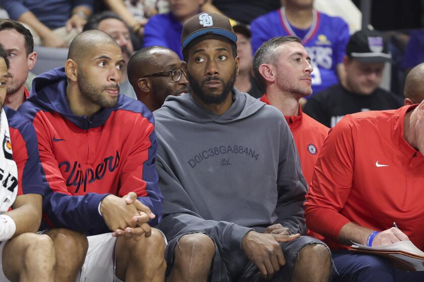 Injured Clippers forward Kawhi Leonard sits on the bench in street clothes during a preseason game