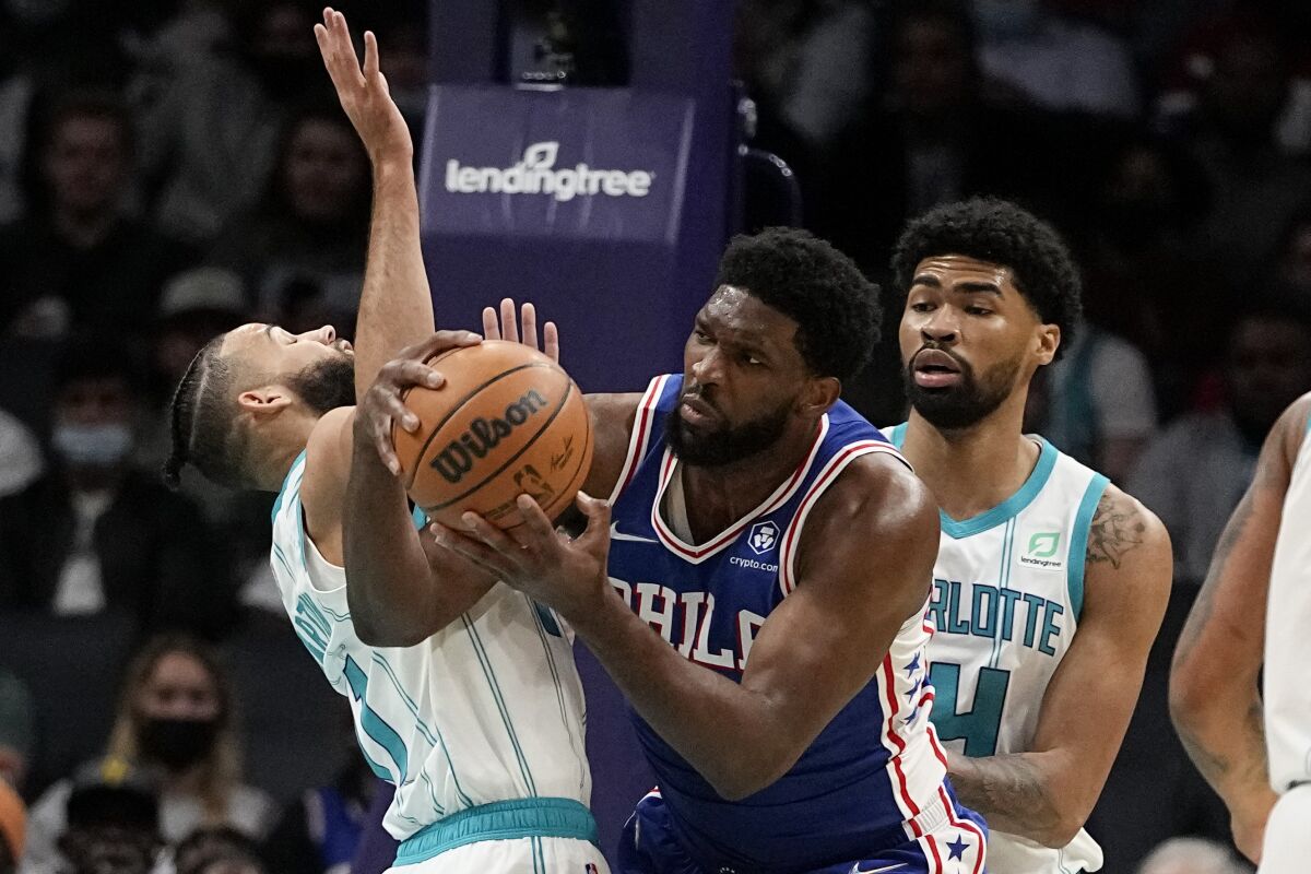 Philadelphia 76ers center Joel Embiid looks to pass between Charlotte Hornets forward Cody Martin, left, and center Nick Richards during the first half of an NBA basketball game on Monday, Dec. 6, 2021, in Charlotte, N.C. (AP Photo/Chris Carlson)