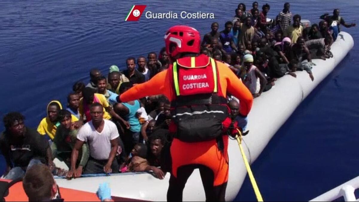 An Italian coast guardsman oversees the Aug. 8 arrival of a refugee-packed boat off the island of Lampedusa, where about 300 may have died Thursday when another overloaded fishing boat caught fire and capsized half a mile offshore.