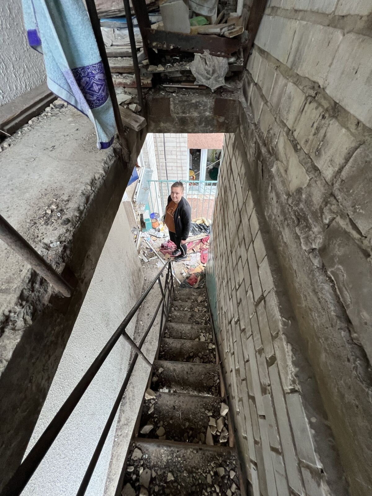 Une femme se tient dans la cage d'escalier d'un immeuble détruit.