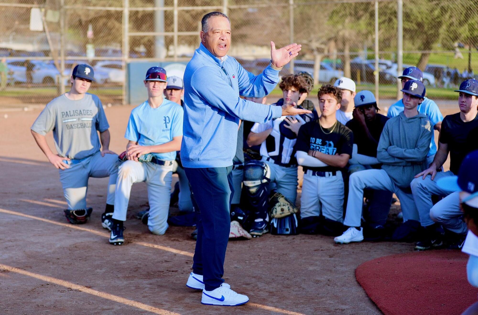 Dodgers yöneticisi Dave Roberts bir sahada duruyor ve Palisades Charter Lisesi beyzbol oyuncuları ile konuşuyor