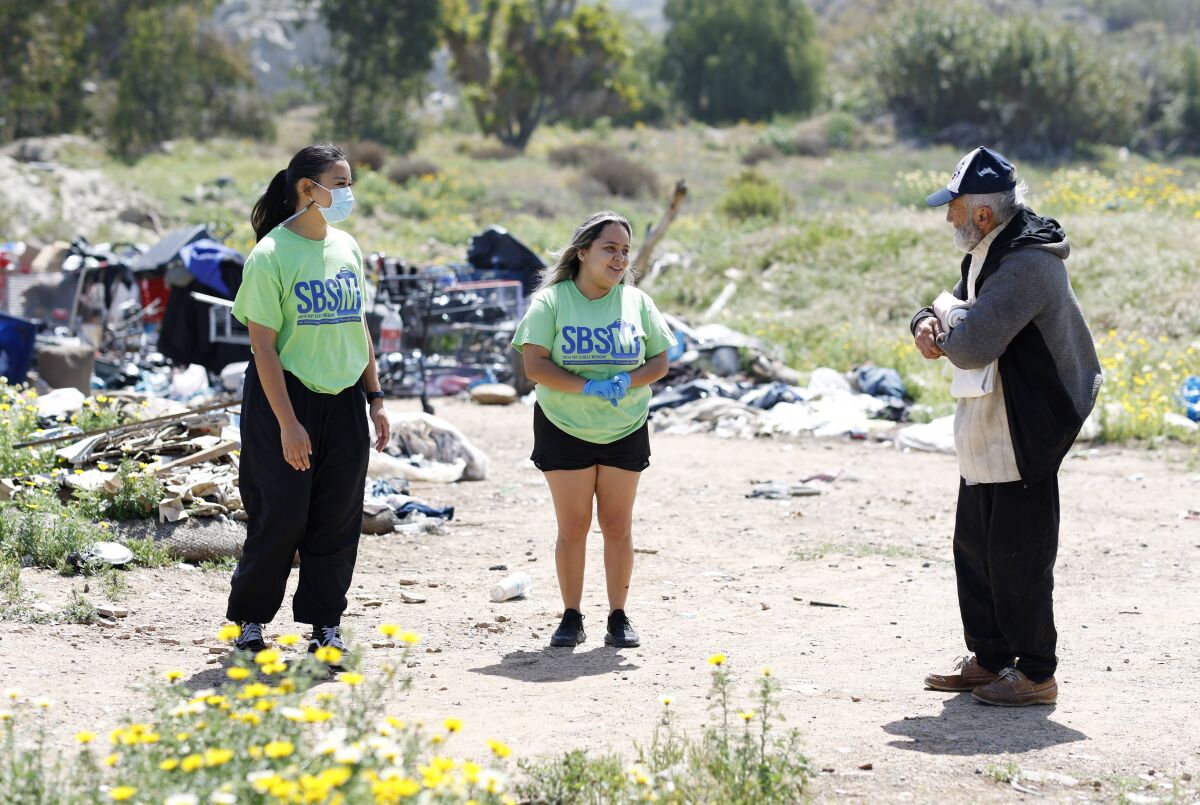 Alyssa Tolentino and Natalie Najera talk with Eduardo Olivas near a homeless encampment in Chula Vista.