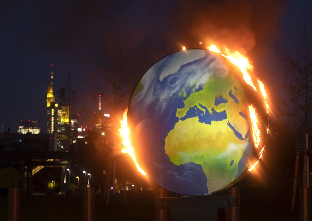 Una maqueta del planeta Tierra arde ante la sede del Banco Central Europeo en Fráncfort, Alemania.