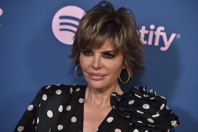 Lisa Rinna in a polka dot blouse posing for pictures at a red carpet event
