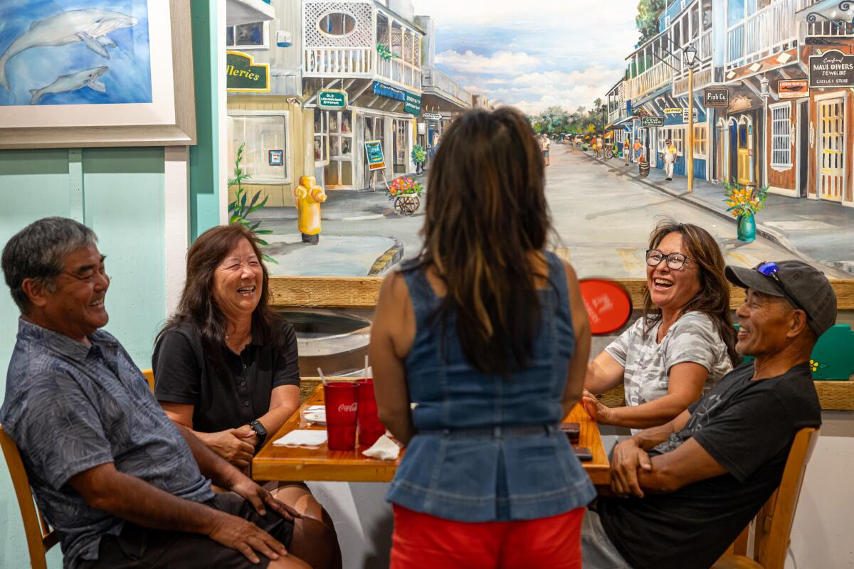 A group of people laugh at a restaurant table.