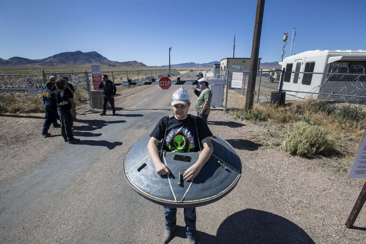 Jacob Dowdle of Chandler, AZ, wears a homemade flying saucer while watching the goings-on at the perimeter fence of Area 51 near the town of Rachel, NV.