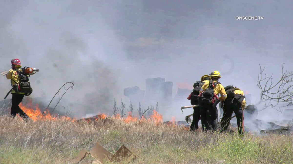 Firefighters battle a brush fire in the Jurupa Valley