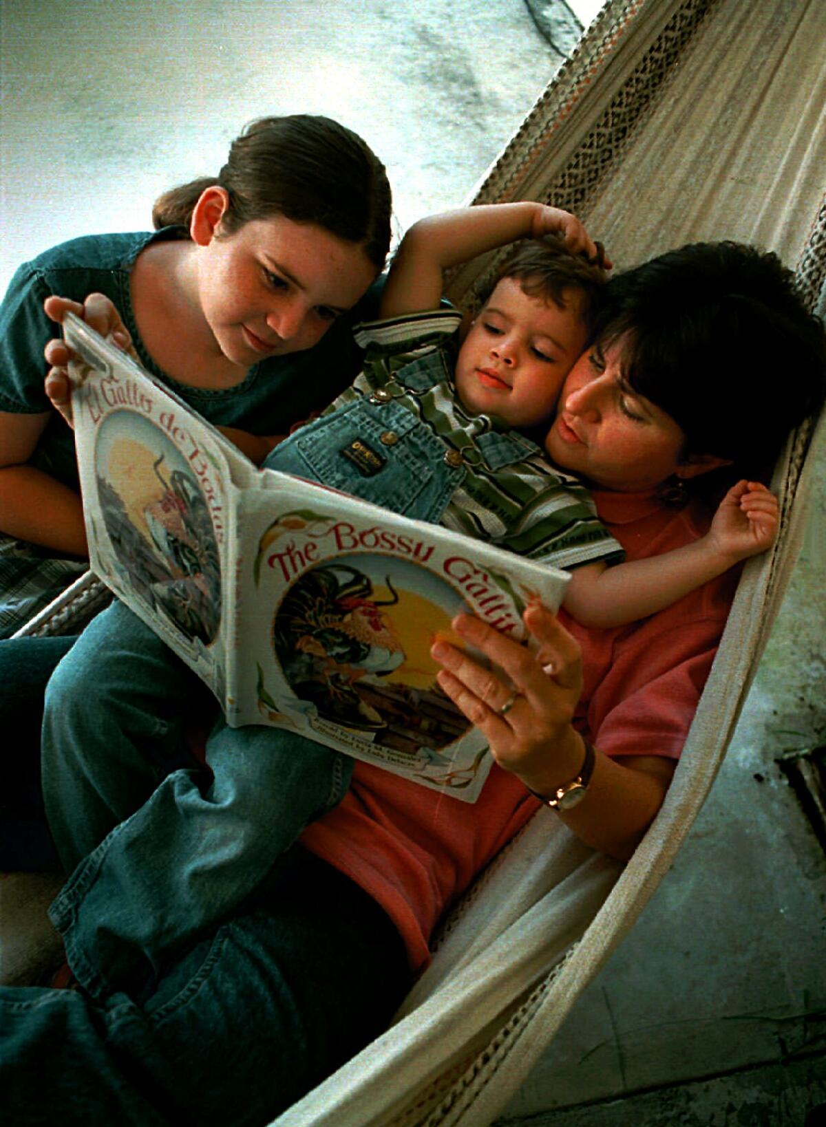Lucía González lee su libro, el "Bossy Gallito" a sus hijos Annie, de 10 años, y José, de 3, en la hamaca en el patio trasero de su casa en Miami, Florida.