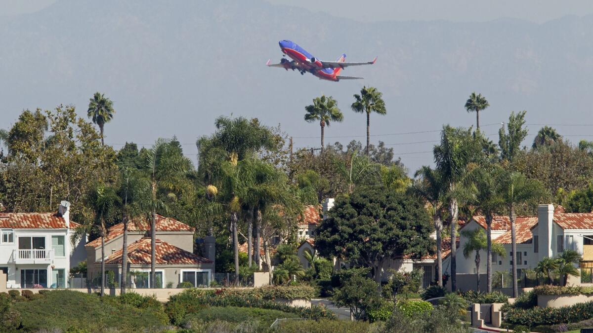 A commercial airplane flies over homes along Upper Newport Bay in Newport Beach after taking off from John Wayne Airport in 2017.