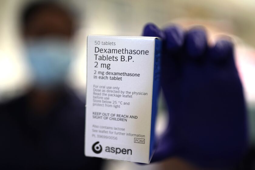 A member of staff at a pharmacy holds a packet of anti-inflammatory drug dexamethasone, in London, Thursday, June 18, 2020. The emergencies chief of the World Health Organization welcomed the news this week that dexamethasone, a cheap steroid, was shown in a British trial to reduce deaths among patients critically ill with the coronavirus, but said it was too soon to change how patients are treated. (Yui Mok/PA via AP)