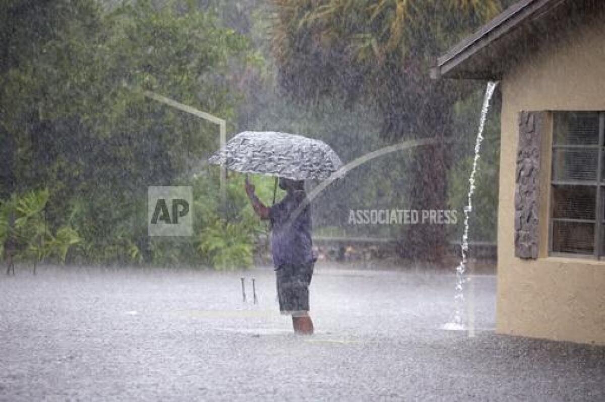 Una persona toma fotografías bajo la lluvia en su barrio inundado por la calle SW 3rd y 4ta Avenida SW