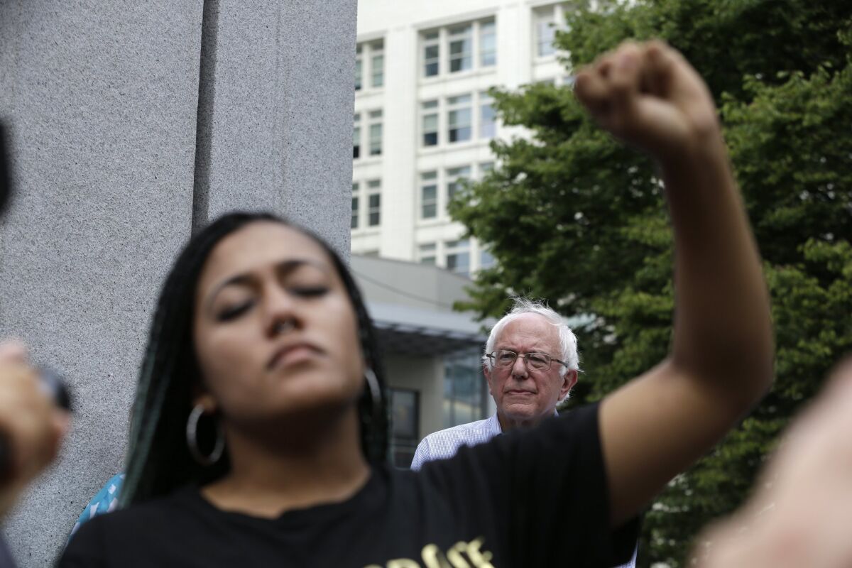 Mara Jacqueline Willaford, a Black Lives Matter activist, holds her fist overhead as Democratic presidential candidate Sen. Bernie Sanders stands nearby at a rally in downtown Seattle.