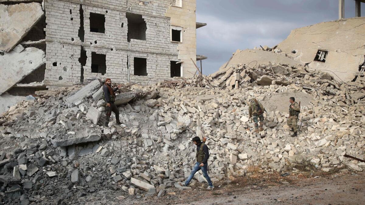 Syrian rebel fighters walk through the rubble of a building destroyed by a reported airstrike west of Aleppo on Monday.
