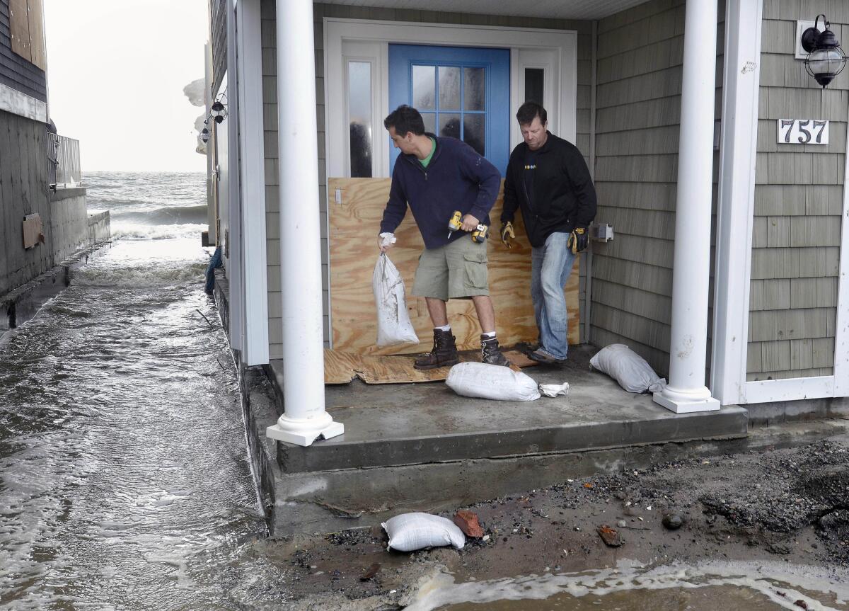 Ken Esposito, left, helps his neighbor Rob Hoxie sandbag his beachfront home before high tide in Milford, Conn., a day after Superstorm Sandy made landfall.