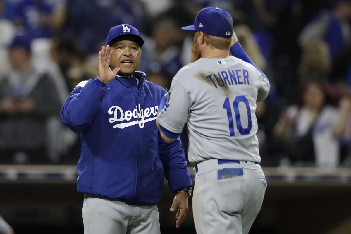 Los Angeles Dodgers manager Dave Roberts, left, celebrates with third baseman Justin Turner (10) after defeating the San Diego Padres 4-3 in a baseball game Friday, May 3, 2019, in San Diego.