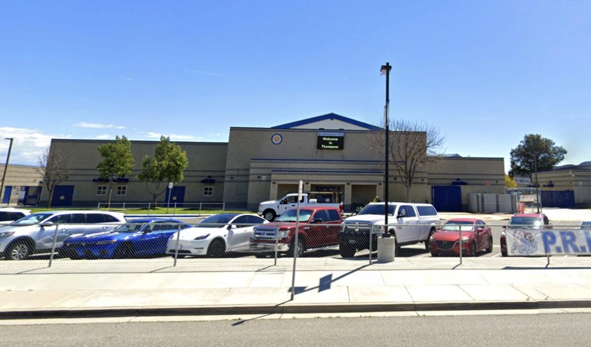 A view of a gray building with cars parked in front