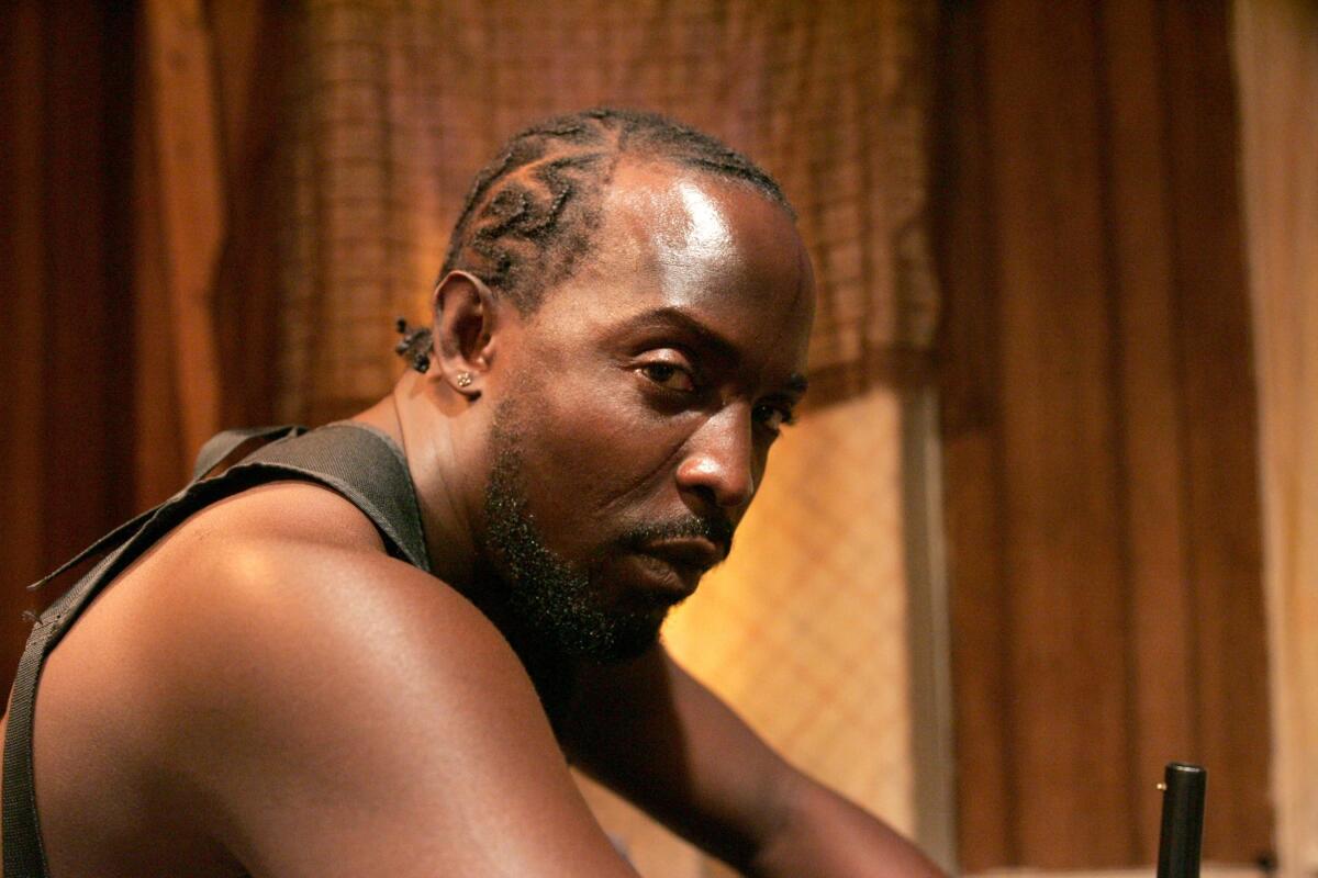 Michael K. Williams, as Omar Little, sits hunched over.