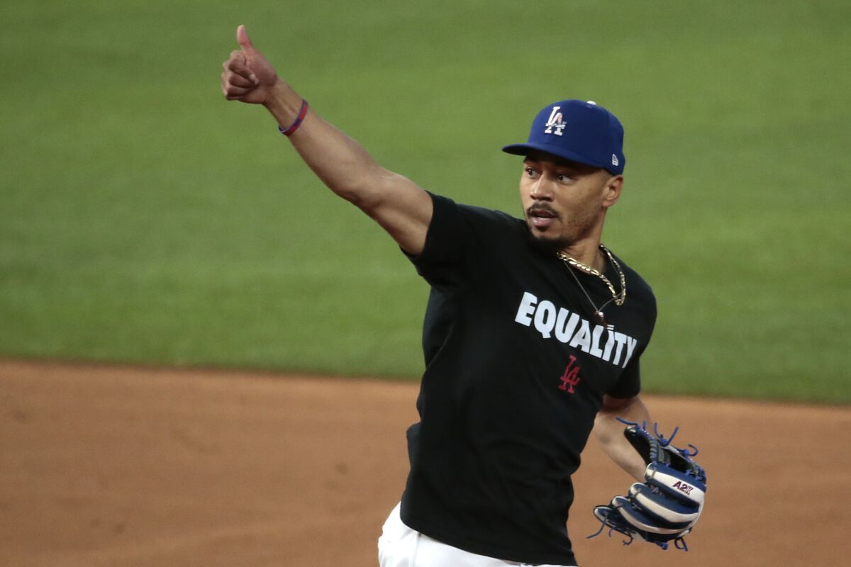 Dodgers right fielder Mookie Betts flashes a thumbs up to coaches during a team workout.