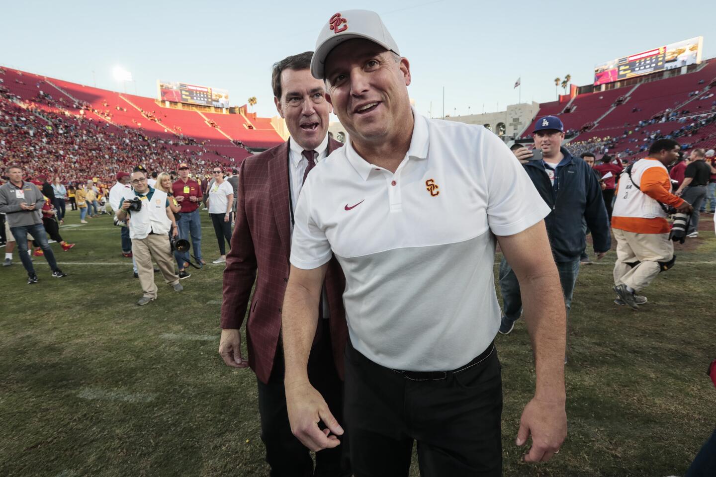 USC head coach Clay Helton and Athletic Director Mike Bohn share a laugh together at midfield after a 52-35 win over UCLA at the Coliseum.