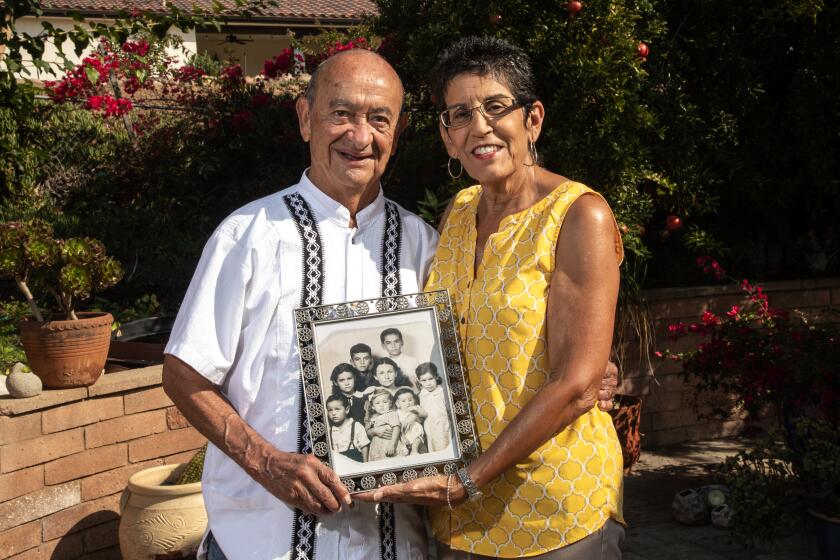 Chula Vista, CA - September 13: Roger Cazares and his wife Norma hold a photograph of Roger's family when he was an infant on Monday, Sept. 13, 2021 in Chula Vista, CA. Roger is the youngest of 7 children in the image.(Jarrod Valliere / The San Diego Union-Tribune)