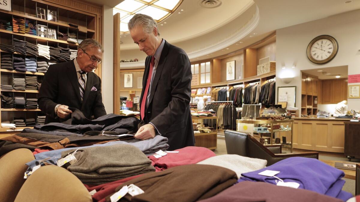 Carroll & Co. general manager Stuart Newmark, left, helps longtime customer Larry Stein with a new jacket.