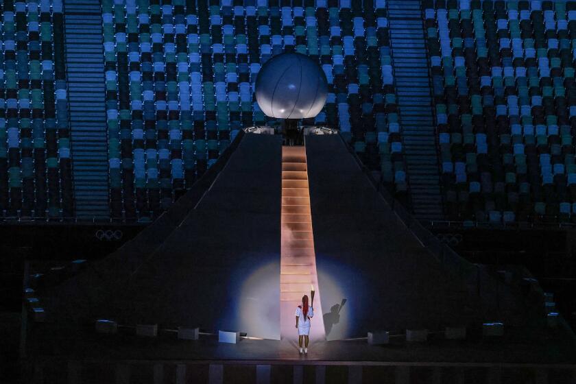 Tokyo, Japan, Friday, July 23, 2021 - Naomi Osaka prepares to scale stairs to light the Olympic flame at the Tokyo 2020 Olympics Opening Ceremony at Olympic Stadium. (Robert Gauthier/Los Angeles Times)