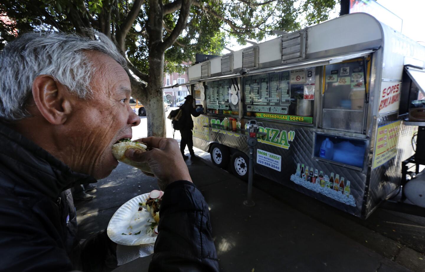 Terril Johnson bites into a taco from the Tacos Ariza food truck in Echo Park, which got a C grade from health inspectors in March but was reinspected and got a B.