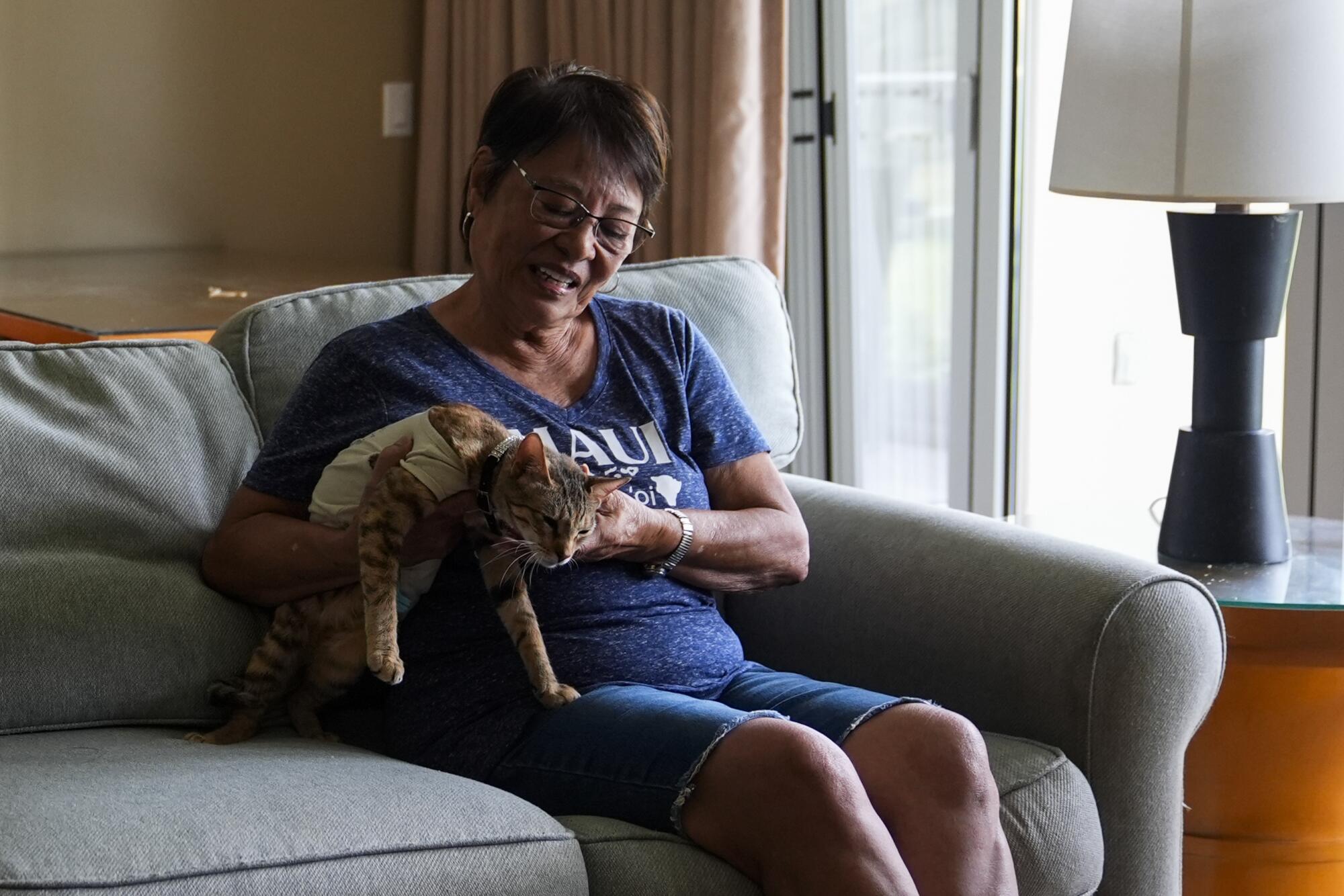 Leola Vierra holds her cat in her temporary room at a resort hotel.