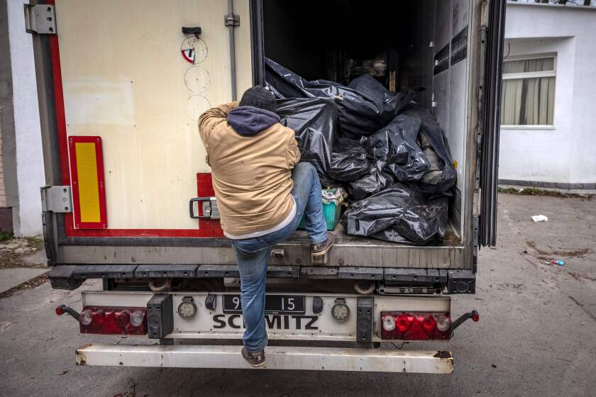 A man in the back of a truck filled with black bags.