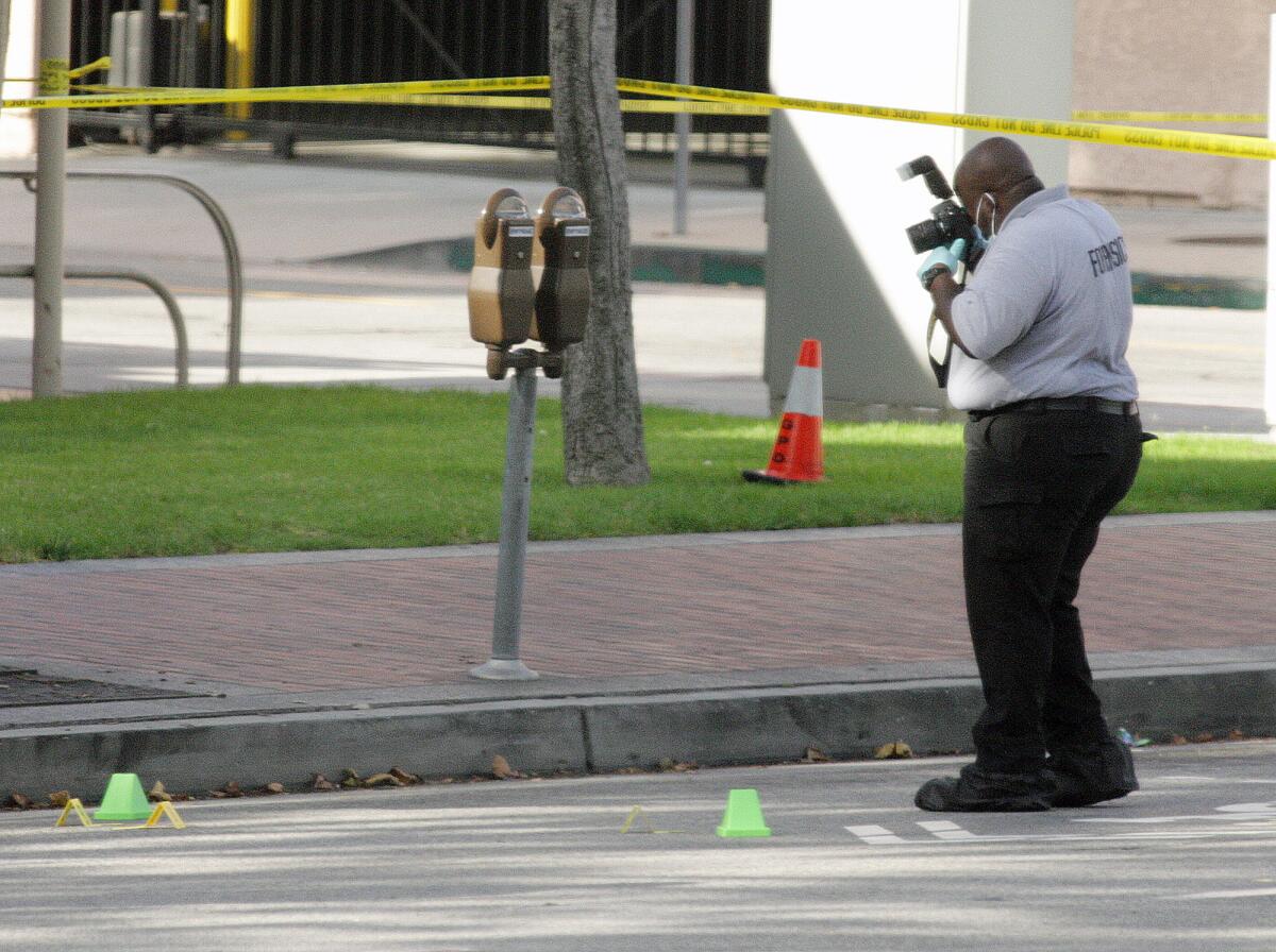 A Glendale Police Department forensics officer takes pictures of evidence lying on Broadway in front of the Glendale Courthouse the morning after a fatal stabbing.