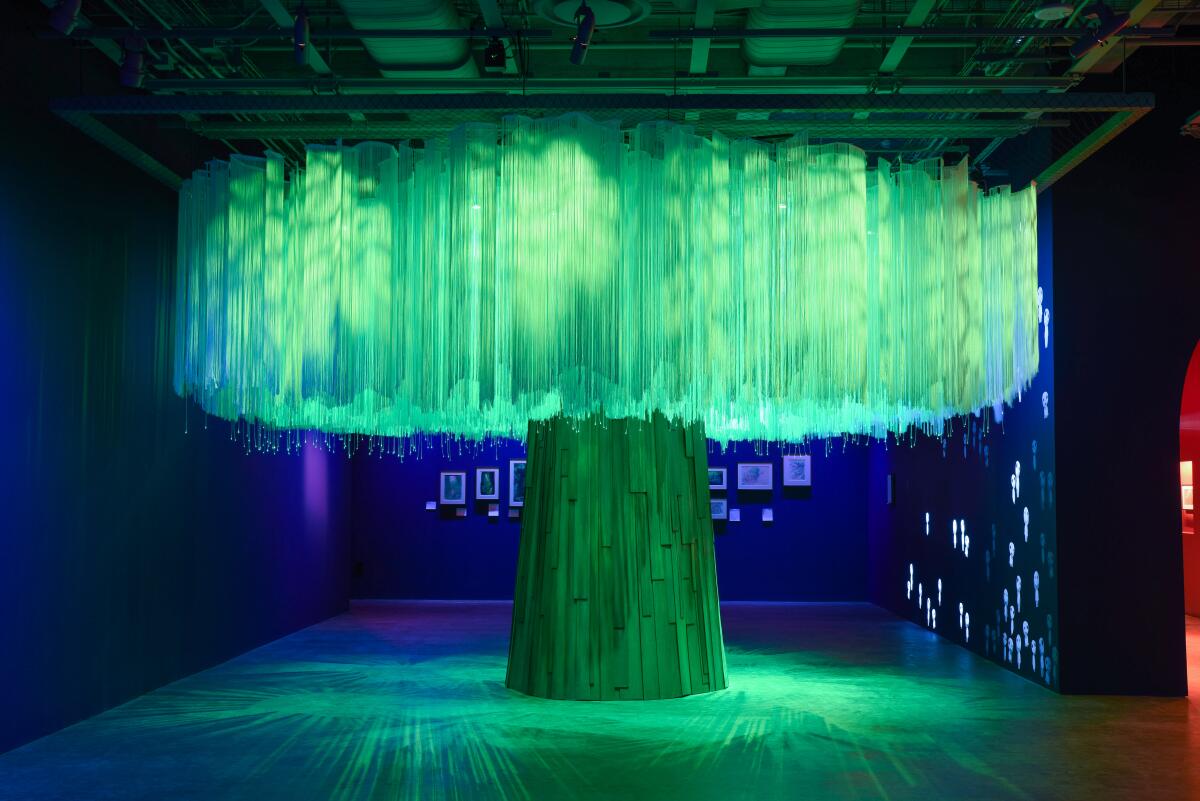 A tree made with branches of string seems to emanate a green light from among its branches