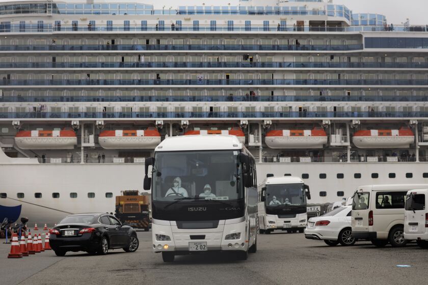 Two buses leave a port where the quarantined Diamond Princess cruise ship is docked Saturday, Feb. 15, 2020, in Yokohama, near Tokyo. A viral outbreak that began in China has infected more than 67,000 people globally. The World Health Organization has named the illness COVID-19, referring to its origin late last year and the coronavirus that causes it. (AP Photo/Jae C. Hong)