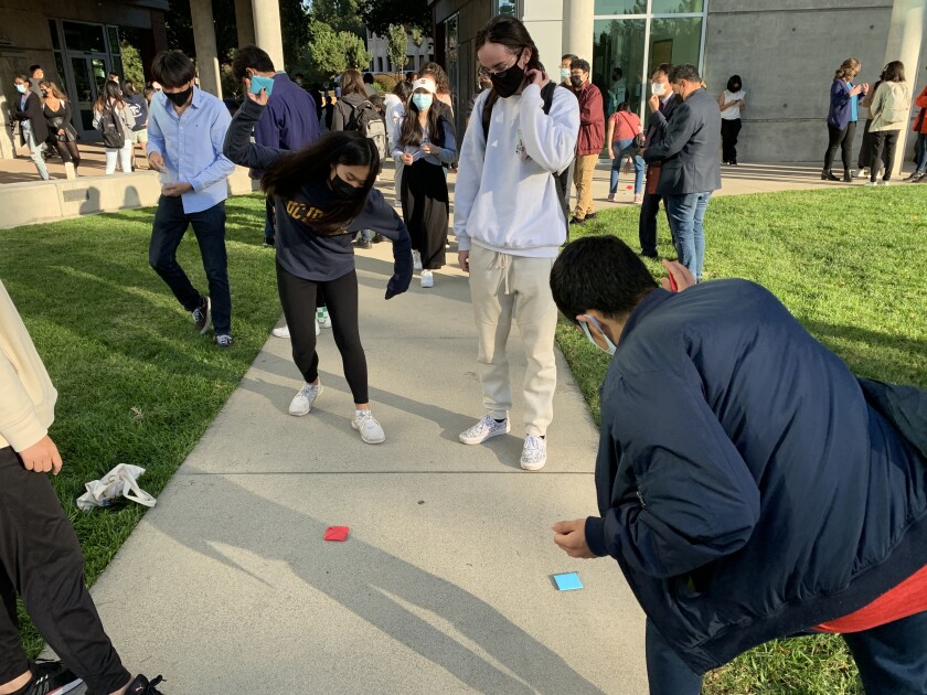 UC Irvine students play a game of ddakji, a traditional South Korean game played using folded paper tiles.