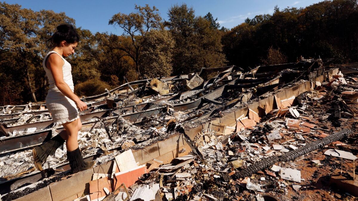 Ashley Oldham, owner of Frost Flower Farms, walks through the ruins of her home destroyed by the Redwood fire.