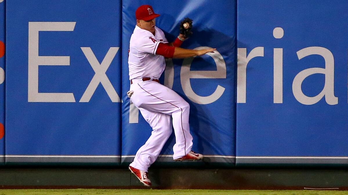 Angels center fielder Mike Trout hits the wall after making a catch for the second out in the sixth inning against the Rangers at Angel Stadium on Sept. 5.