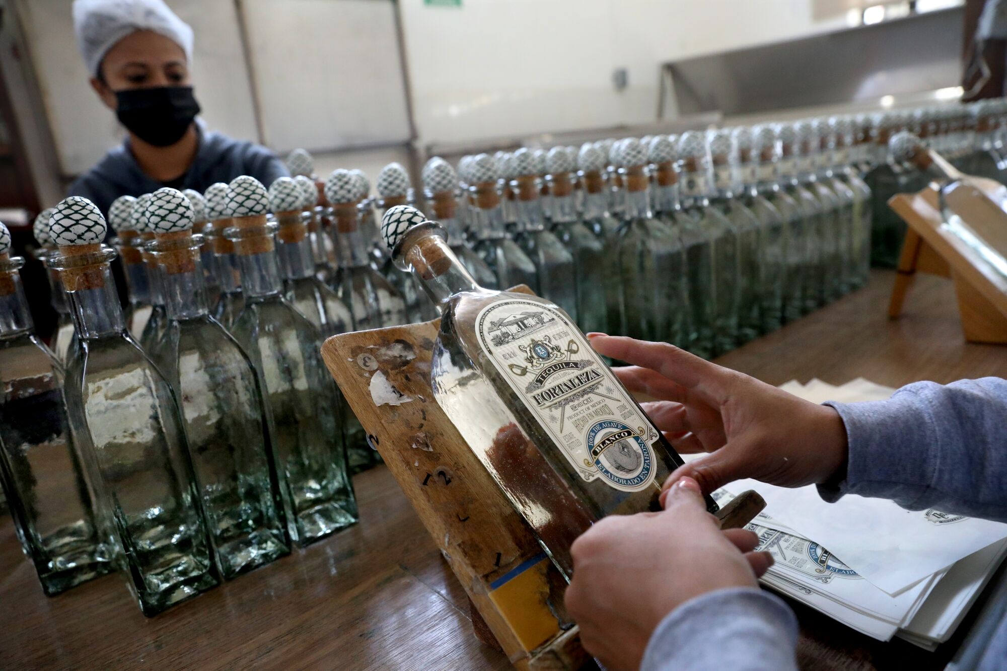 Workers place labels by hand on bottles of tequila