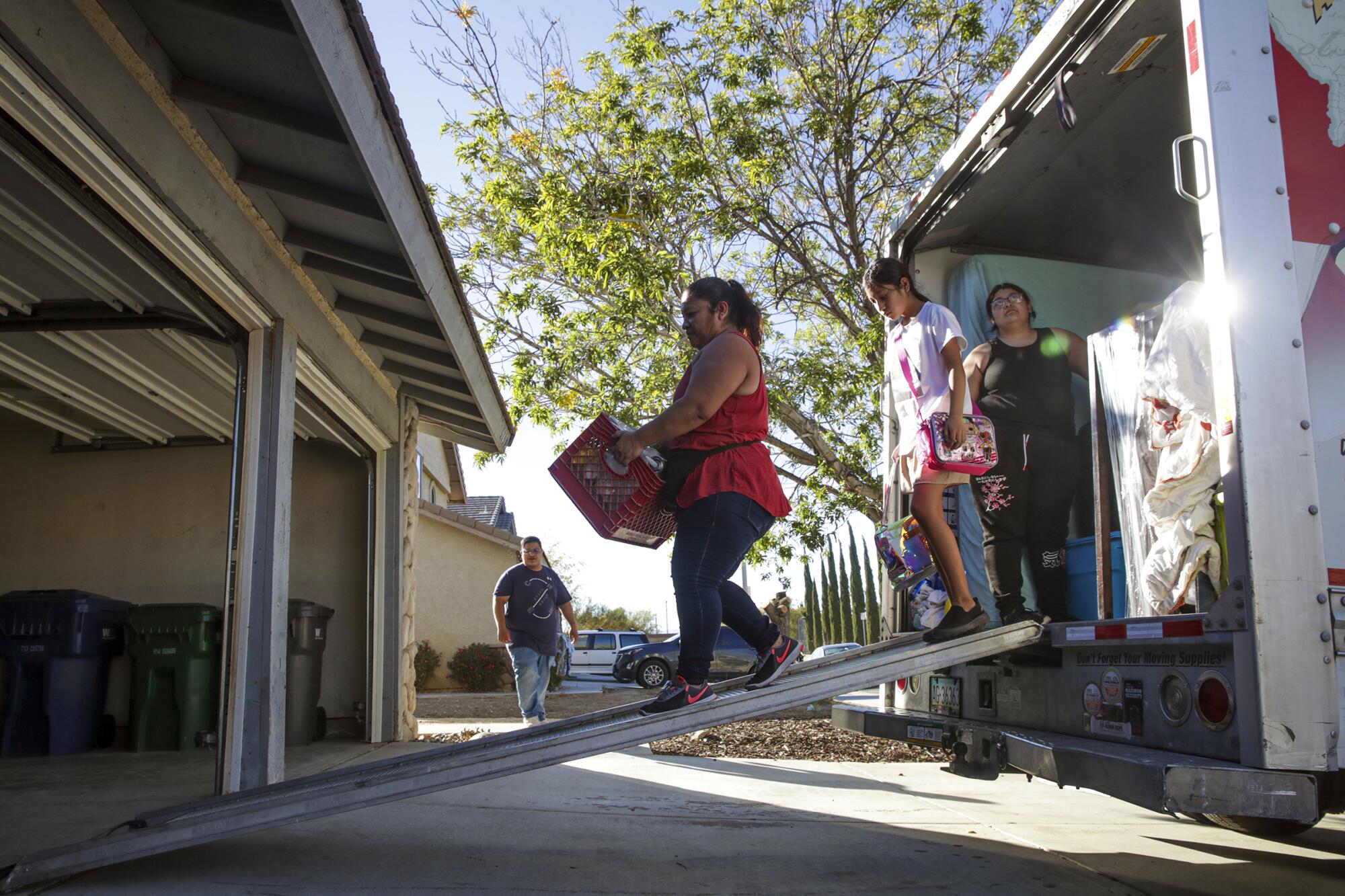 Juana Oceguera and her family unload their U-Haul after relocating to a four-bedroom home in Lancaster.