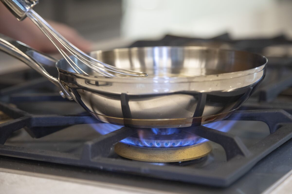 A pan is shown on the burner of a gas stove.
