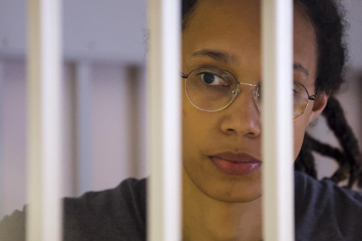WNBA star and two-time Olympic gold medalist Brittney Griner looks through bars as she listens to the verdict standing in a cage in a courtroom in Khimki just outside Moscow, Russia, Thursday, Aug. 4, 2022. A judge in Russia has convicted American basketball star Brittney Griner of drug possession and smuggling and sentenced her to nine years in prison. (Evgenia Novozhenina/Pool Photo via AP)