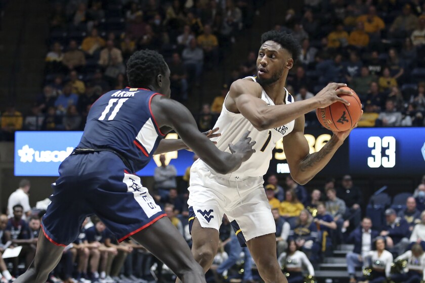 West Virginia forward Pauly Paulicap (1) is defended by Connecticut forward Akok Akok (11) during the second half of an NCAA college basketball game in Morgantown, W.Va., Wednesday, Dec. 8, 2021. (AP Photo/Kathleen Batten)
